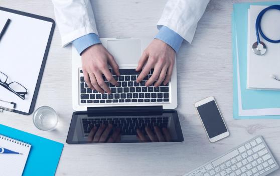 Doctor working on desk with computer